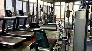 Ett gym med löpband, styrketräningsmaskiner och ett stort fönster.
