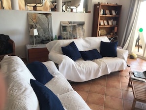 A living room with two white sofas, dark blue cushions, a wooden side table, and a bookshelf. - 5+1 bedroom family villa with pool and sea view, Vedra and wooded hills (Sant Josep de sa Talaia)