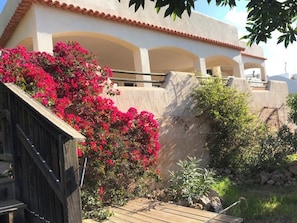 A building with a white facade, terracotta roof tiles, and a wooden deck. - 5+1 bedroom family villa with pool and sea view, Vedra and wooded hills (Sant Josep de sa Talaia)