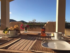 A wooden table with a white cup, a plate, and a small vase with flowers. - 5+1 bedroom family villa with pool and sea view, Vedra and wooded hills (Sant Josep de sa Talaia)