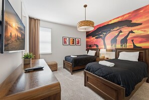 A hotel room with two beds, a TV, a desk, a lamp, and a large painting of giraffes and trees. - Upscale 9BR Stay with Pool and Themed Rooms (Kissimmee)