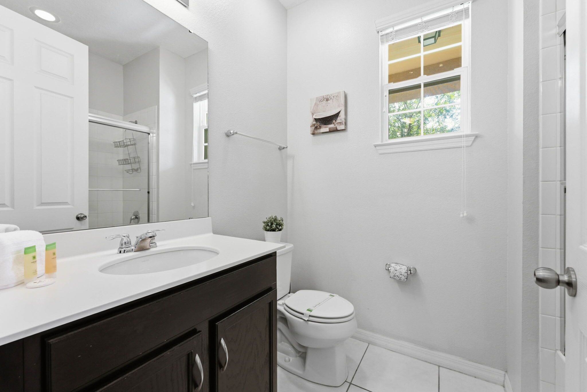 Une salle de bain avec un lavabo blanc, un miroir et des toilettes.