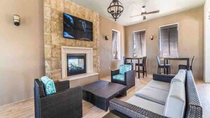 Ein modernes Wohnzimmer mit Steinwand, Flachbildfernseher, Kamin und Sitzgelegenheit im Freien.
