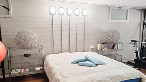 A bedroom with a bed, a workout bike, and a shelf with books and a ball. - Elegant Villa With Pool (Senigallia)