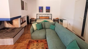 A living room with a sectional sofa, a fireplace, a bed with a headboard, and two wall-mounted paintings. - Elegant Villa With Pool (Senigallia)