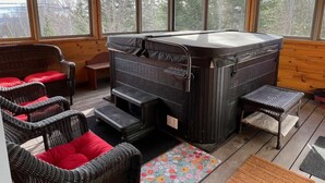 Een knus vertrek met een sauna, rieten meubels en grote ramen.
