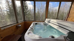 Een hottub in een houten chalet met grote ramen.
