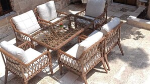An outdoor seating area with wicker furniture and a stone wall backdrop. - MAROVA BOUTIQUE HOTEL (Artuklu)