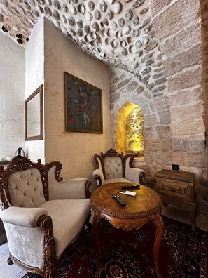 Une pièce avec un mur en pierre, un tableau, un canapé, une table et un meuble en bois.