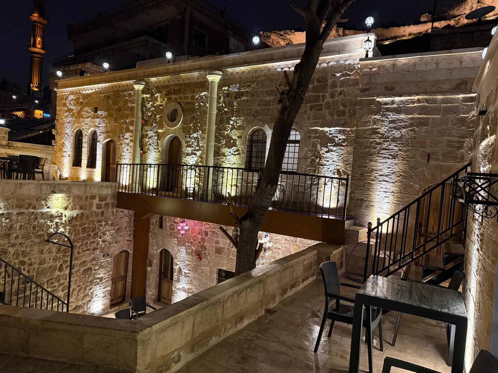 A stone building with a balcony, a staircase, and a tree.