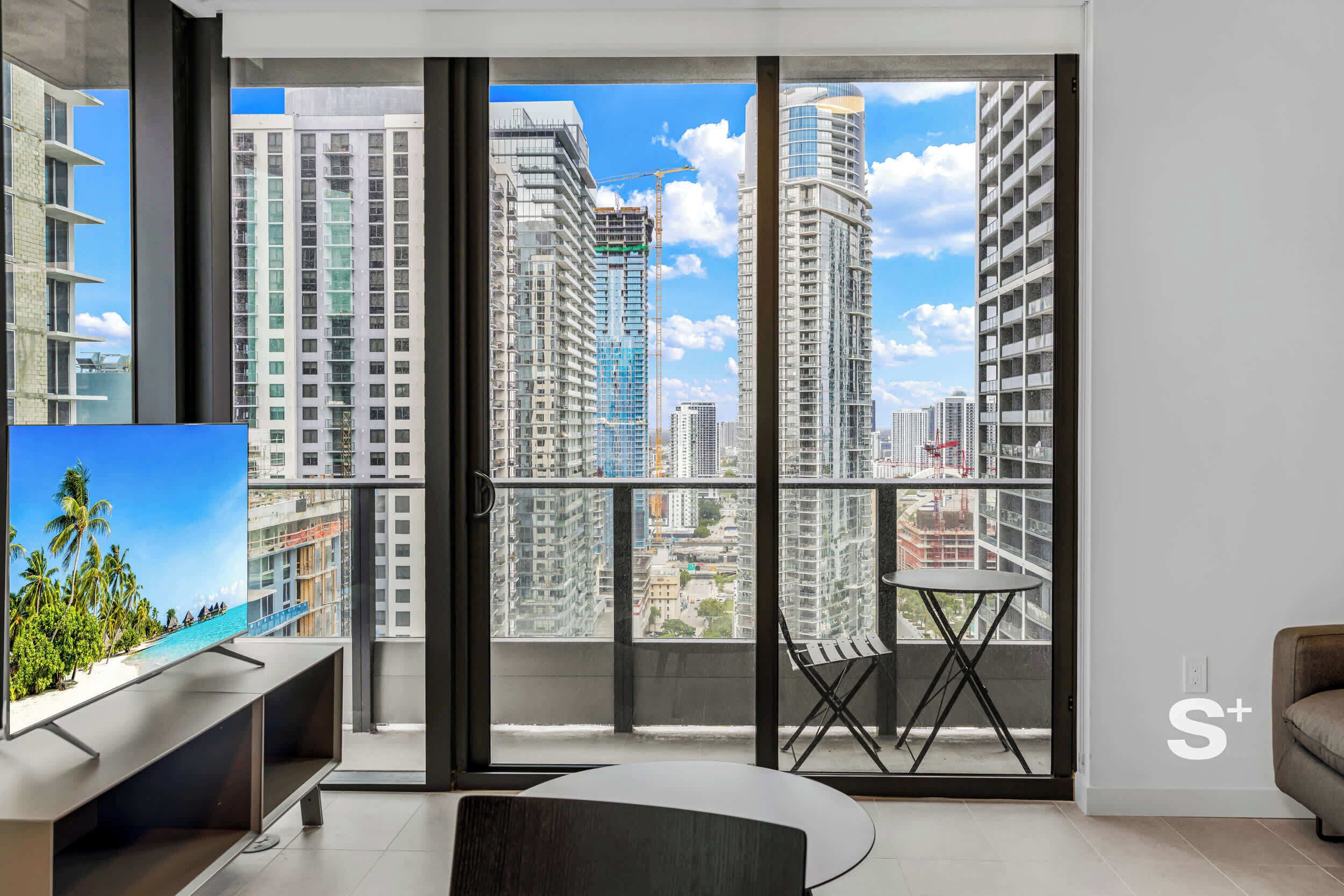 A modern apartment with a balcony, a TV, and a small table.