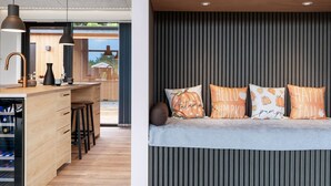 A modern kitchen with wooden cabinetry, a bar area, and a seating area with cushions. - "Sharina" - 320m to the fjord by Interhome (Storvorde)