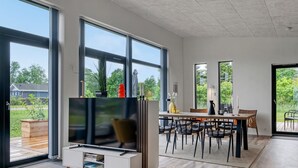 A modern living room with a TV, dining area, and large windows. - "Sharina" - 320m to the fjord by Interhome (Storvorde)
