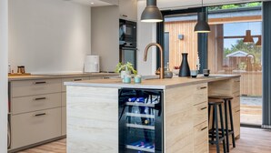 A modern kitchen with a central island, pendant lighting, and a view to the outside. - "Sharina" - 320m to the fjord by Interhome (Storvorde)