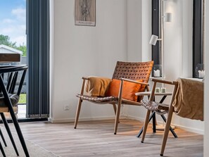 Et moderne værelse med en flettet stol, et bord og en lampe.