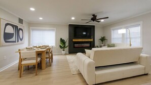 Un salon comprenant un canapé, une table à manger, des chaises, un téléviseur et un ventilateur de plafond.