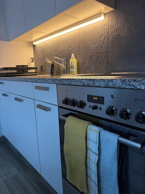 A modern kitchen with a built-in oven, a microwave, and a coffee machine. - At the muschaliks (Knonau)