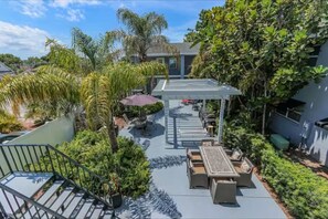 A covered outdoor patio with seating, surrounded by lush greenery and a staircase. - Hyde Park Modern 1 Bedroom – Walk to Everything! (Tampa)