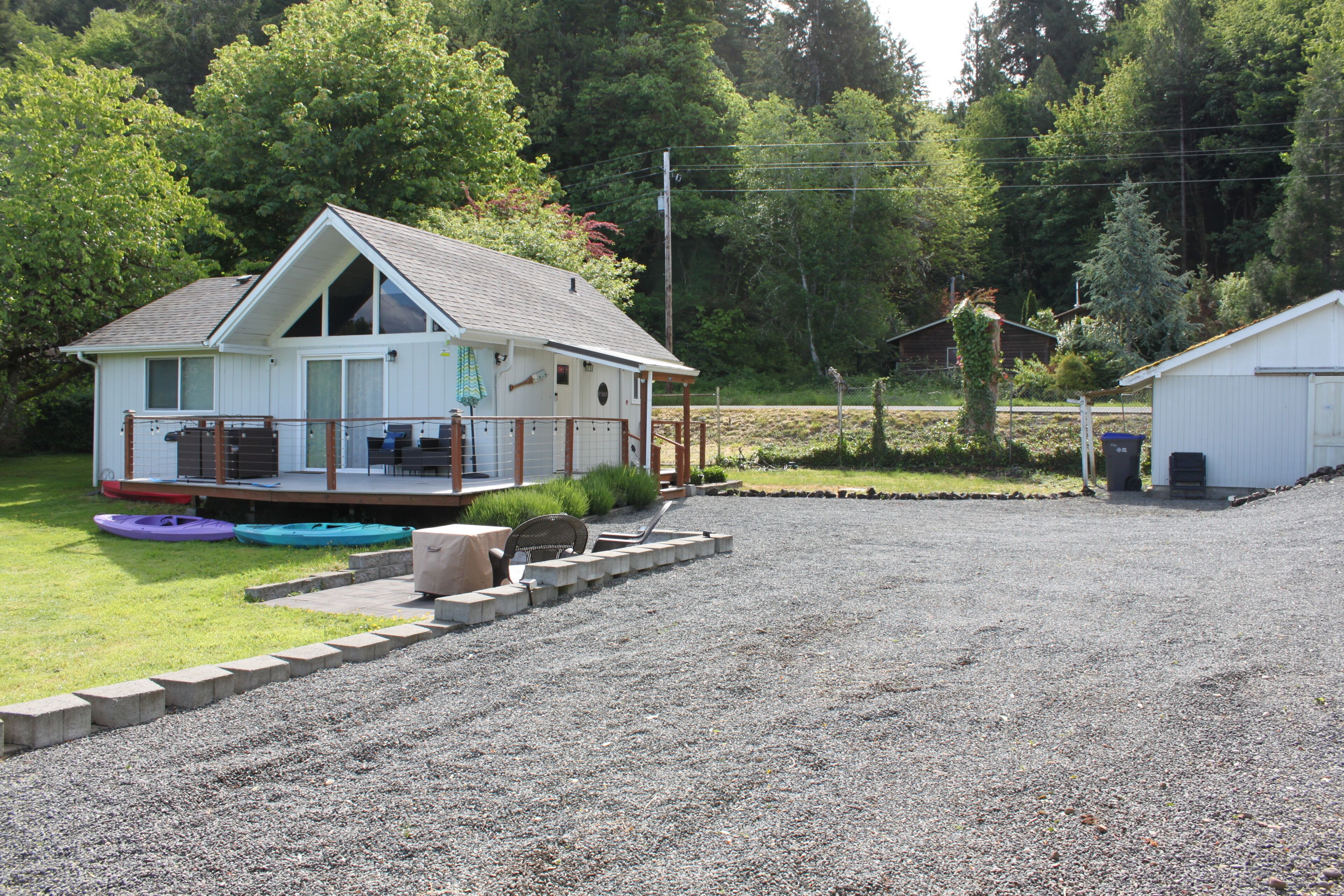 A two-story house with a porch, a covered deck, and a gravel driveway.
