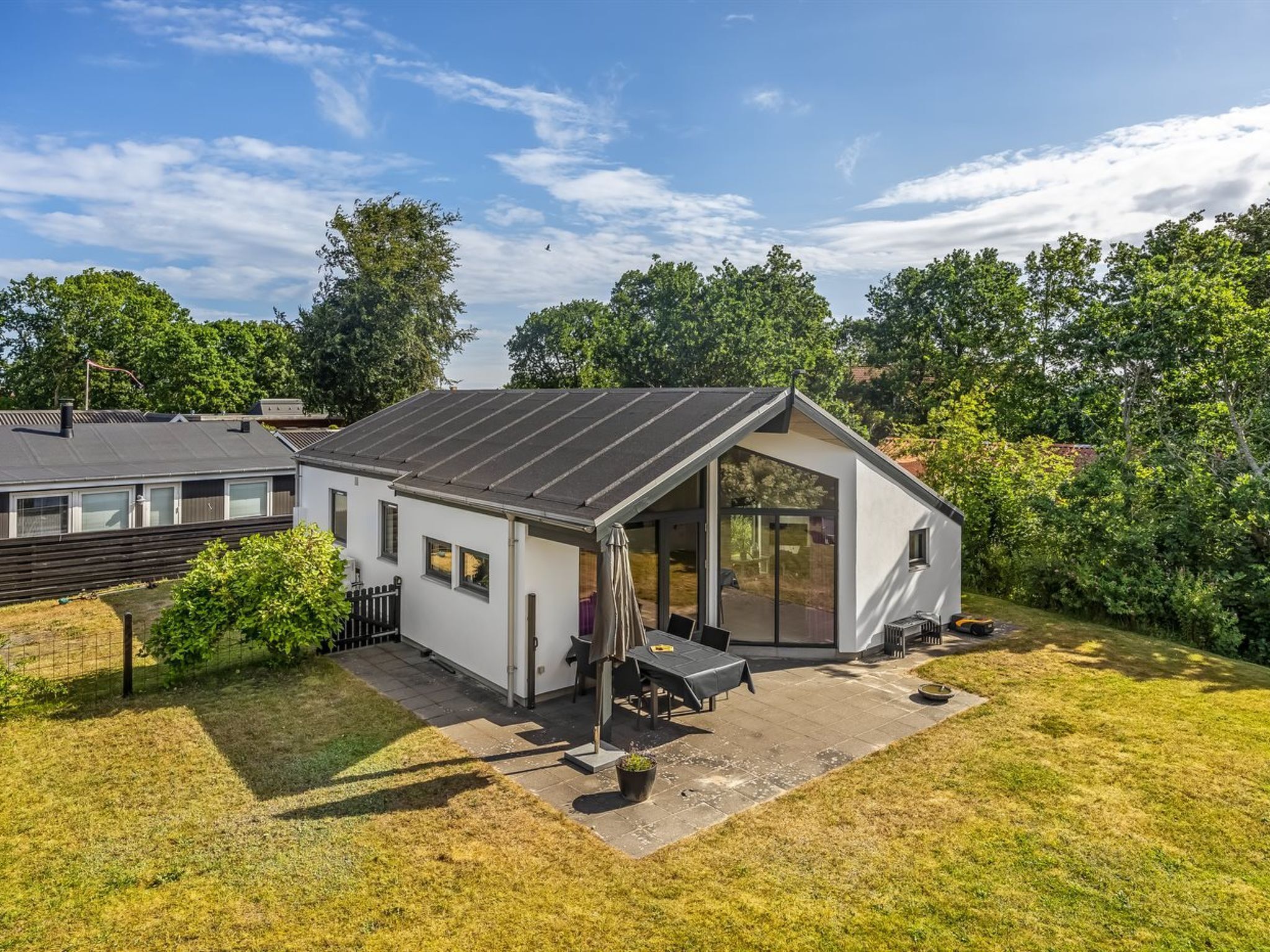 A modern house with a large patio, a covered outdoor seating area, and a solar panel roof.