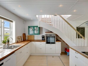 Eine moderne Küche mit weißen Schränken, einer Holz Arbeitsplatte und einem eingebauten Backofen.