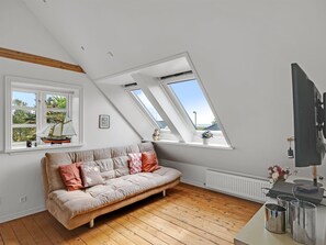 Une pièce de style « loft », avec un canapé, des fenêtres de toit, un radiateur et une vue sur l’extérieur.