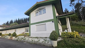 Un bâtiment à deux étages, doté d’une façade verte et blanche, d’un porche couvert et d’une allée gravillonnée.