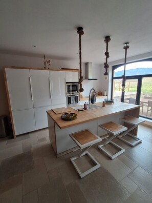 A modern kitchen with a central island, built-in appliances, and a view of the outdoors.