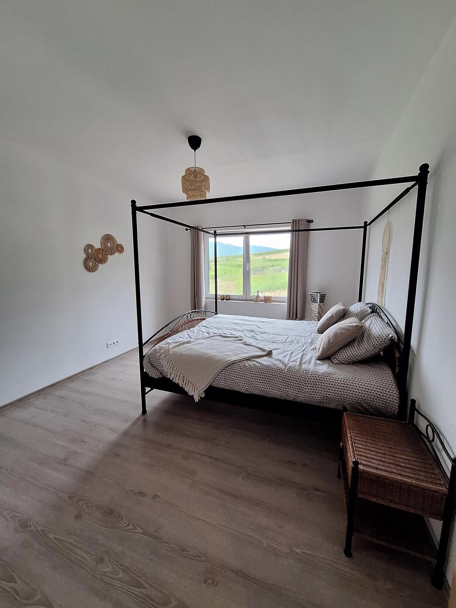 Un lit à baldaquin avec une tête de lit en bois, une table de chevet et un banc.