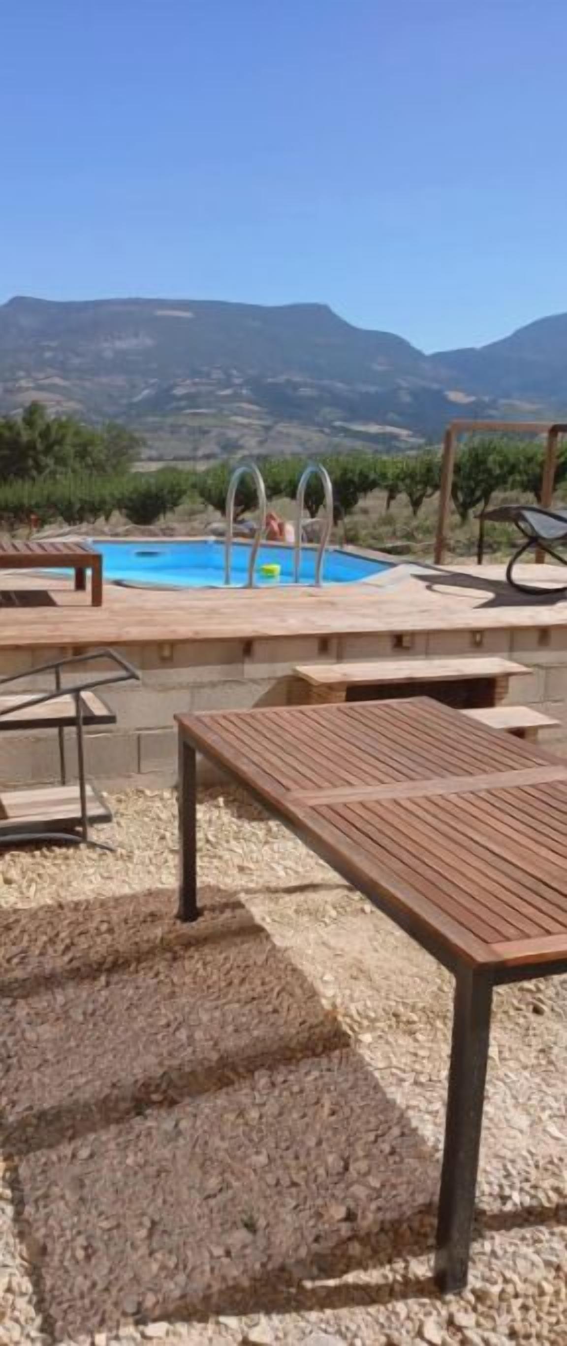 Un espace extérieur avec piscine, des bancs en bois et une vue sur les montagnes.
