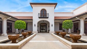 A building with a central entrance, two symmetrical wings, and a fountain in the middle.