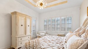 A bedroom with a large bed, a wardrobe, and a window with shutters.