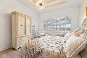 A bedroom with a large bed, a wardrobe, and a window with shutters. - Spacious 3-bedroom condo within the main gate of Miromar Lakes (Miromar Lakes)
