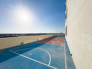An outdoor basketball court with a clear view of the surrounding area, including a bridge and distant buildings. - Free Housekeeping Visits During Your Stay - Stayshort - Comfortable 1 Bed in Jebel Ali Sleeps 2 With Balcony (Dubai)