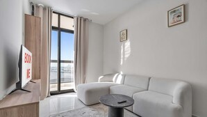 Una sala de estar moderna con un sofá blanco, una mesa redonda de centro y un ventanal con cortinas.