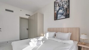Una habitación de hotel con una cama, una mesita de noche, un cuadro y una puerta.