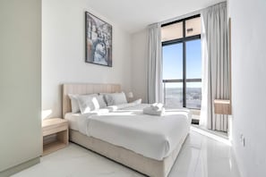 A modern hotel room with a large bed, a nightstand, a painting on the wall, and a view of the city through the window. - Free Housekeeping Visits During Your Stay - Stayshort - Comfortable 1 Bed in Jebel Ali Sleeps 2 With Balcony (Dubai)