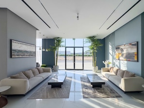 A modern living room with two sofas, a coffee table, and large windows. - Free Housekeeping Visits During Your Stay - Stayshort - Comfortable 1 Bed in Jebel Ali Sleeps 2 With Balcony (Dubai)