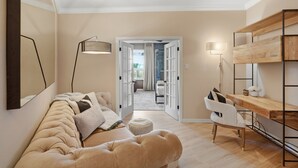 En moderne stue med en sofa, et skrivebord og en stol. Der er en dør, som fører til et andet rum.