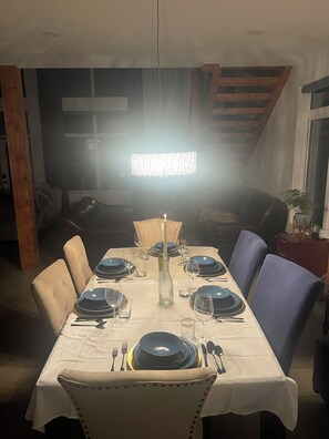 A dining area with a table set for four, featuring a white tablecloth, blue plates, and a candle centerpiece.