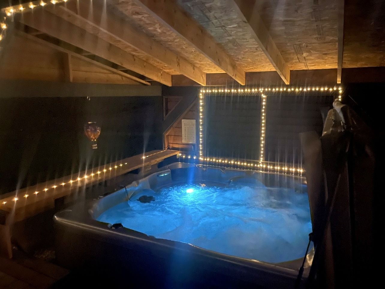 A hot tub with a wooden ceiling and string lights.
