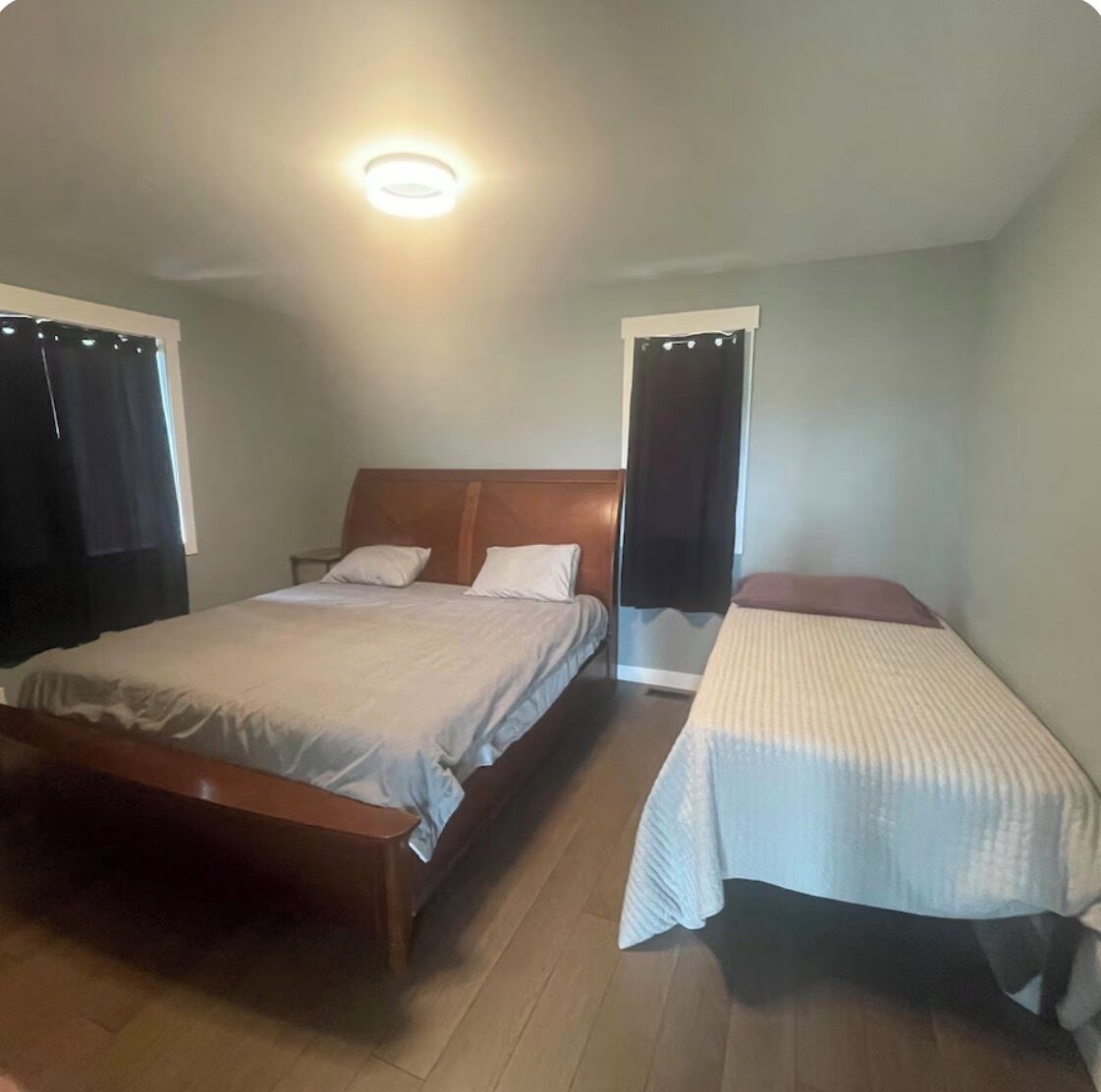 A bedroom with a large bed, a smaller bed, and a nightstand.