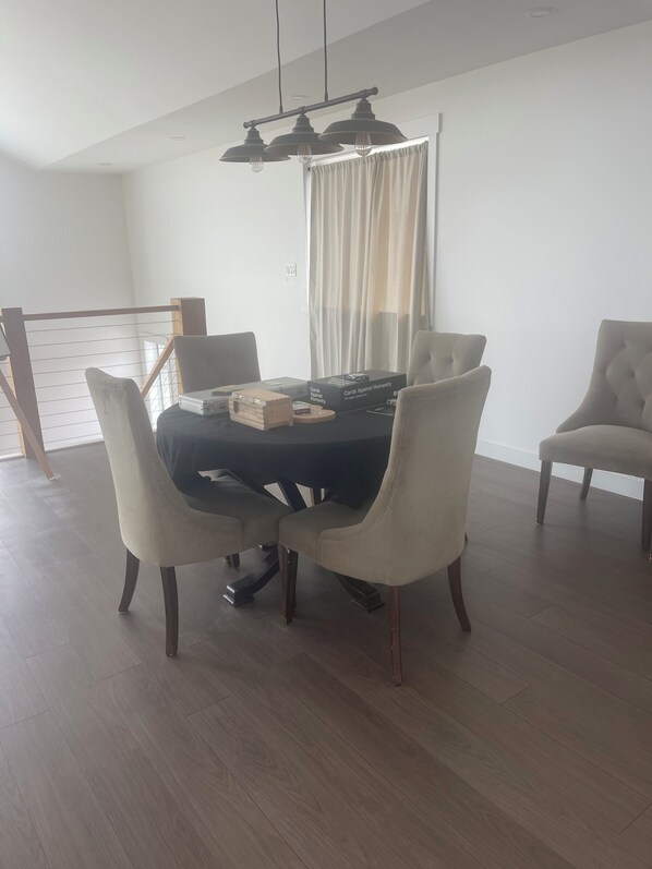 A dining area with a round table, six chairs, and a chandelier.