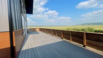 A wooden deck with a view of a green landscape.