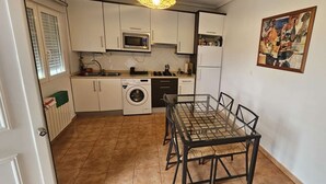 A compact kitchen with a washing machine, microwave, and dining table with chairs. - Bizkar Bare Apartamento 4 (Sopuerta)