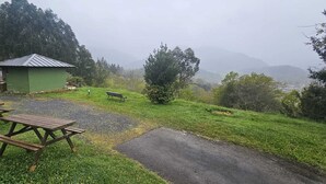 A picnic area with benches and a small shed, surrounded by grassy terrain and trees. - Bizkar Bare Apartamento 4 (Sopuerta)