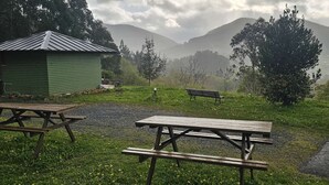 Ein Picknickbereich mit Bänken und Tischen, eine kleine Werkstatt und Blick auf Berge.