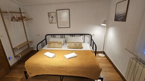Ein Schlafzimmer mit einem Bett, zwei Kissen, einem Nachttisch, einer Lampe, einem gerahmten Bild und einer Tür.
