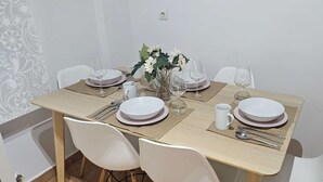 Ein Esstisch ist gedeckt mit Tellern, Gläsern und einer Blumenvase.