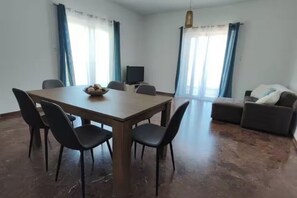Una habitación con una mesa de comedor, sillas, un sofá y un televisor.